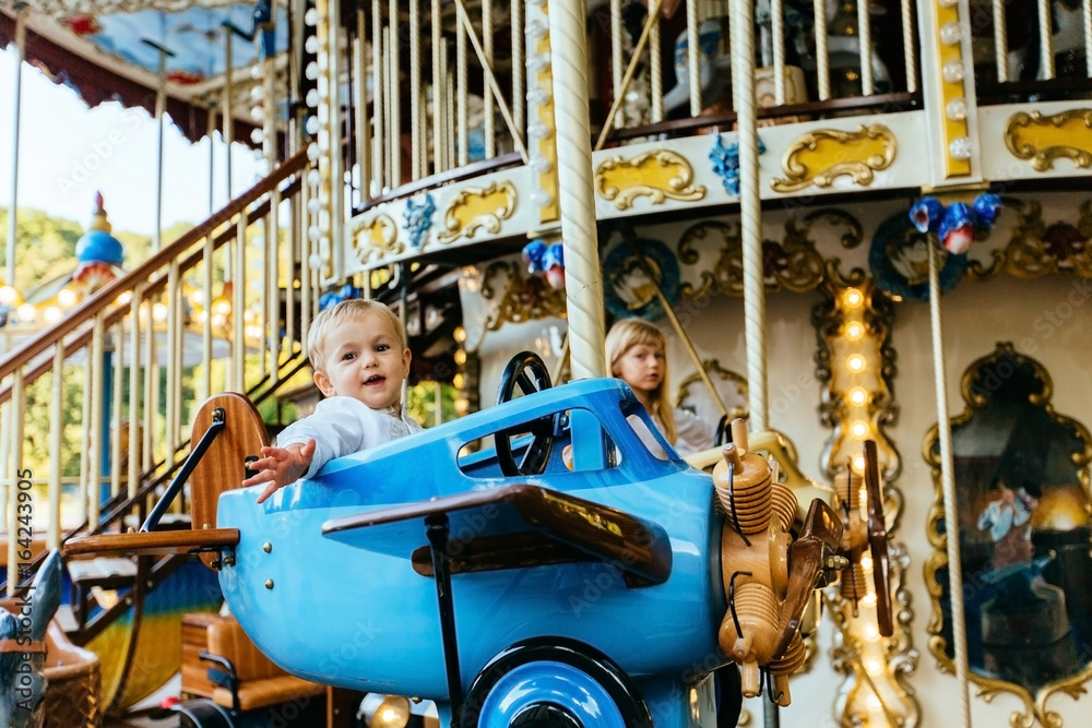 Cute blond toddler baby boy on a carousel