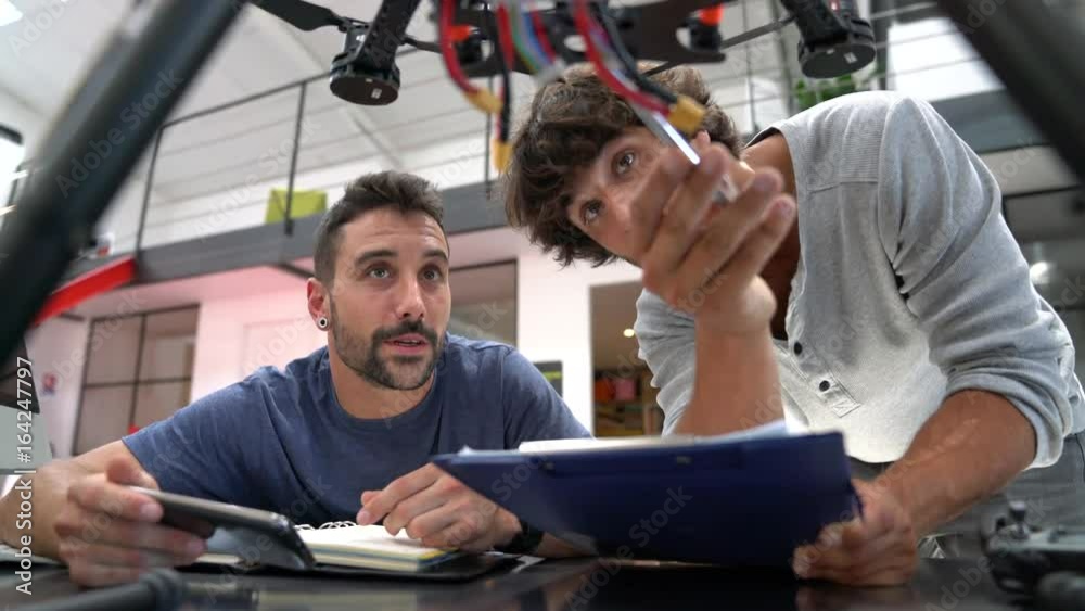 Engineer and technician working together on drone in office