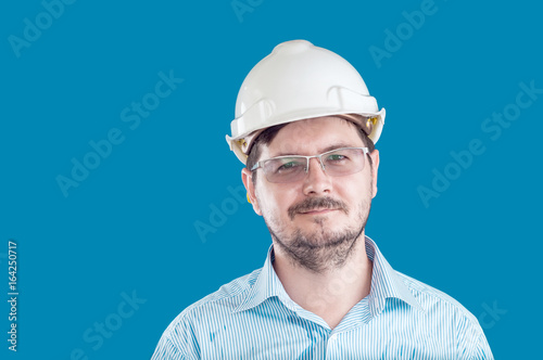 Wallpaper Mural Handsome 30 years old task manager with construction helmet and glasses on blue background Torontodigital.ca