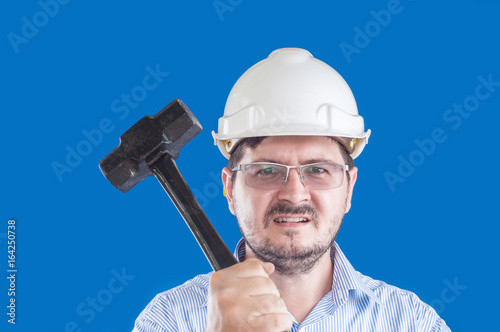 Crazy angry boss with heavy black hummer and construction helmet on violet background