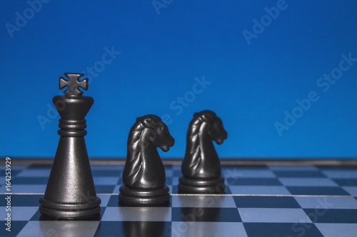 Chess as a business. A black figure controls two black horses.