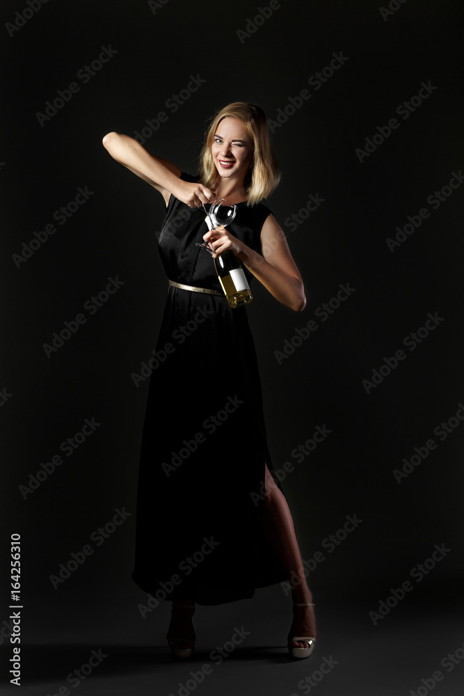 Beautiful blonde woman holding white wine bottle on black background. Party and holiday