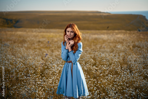 Beautiful young woman in a field of flowers in the mountains by the sea