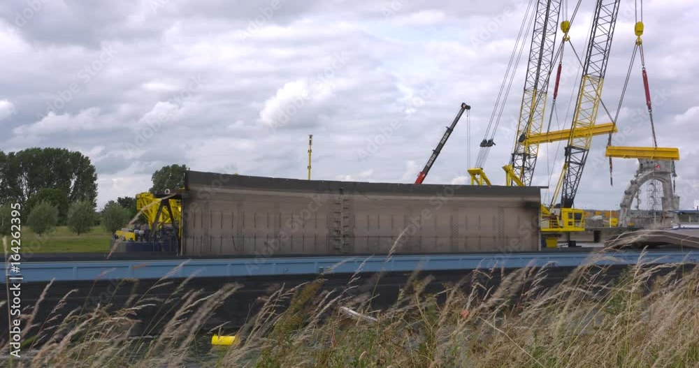 transport of flood gate in a barge, crane vessel in background. The weir ensemble Nederrijn & Lek requires renovation after some 50 years of operation. AMERONGEN, THE NETHERLANDS - JUNE 2017 transport of flood gate in a barge, crane vessel in background. The weir ensemble Nederrijn & Lek requires renovation after some 50 years of operation. AMERONGEN, THE NETHERLANDS - JUNE 2017