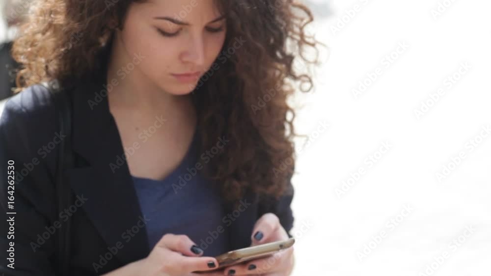 Beautiful young woman with a smartphone in the hands of the city