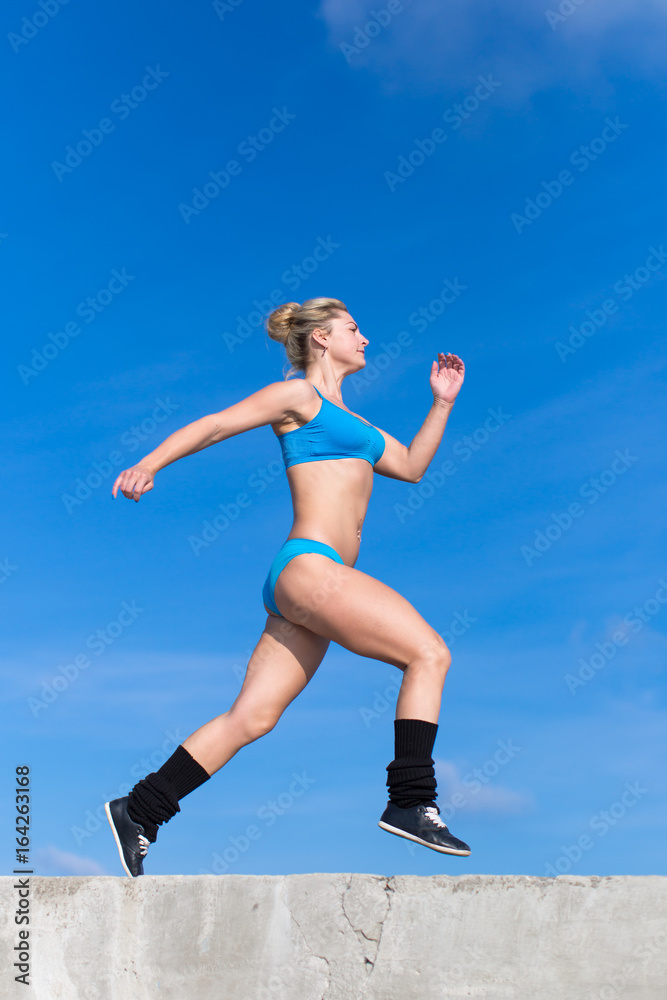 Young woman in sportswear running along seafront Young woman in sportswear running along seafront