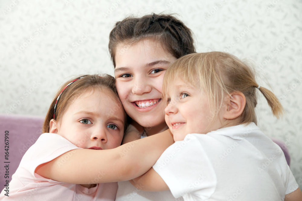 Three sisters  in   embrace on   couch