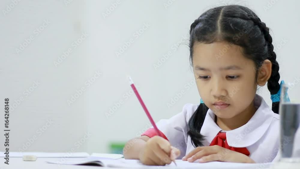 Asian little girl in Thai kindergarten student uniform doing home work close up shot Asian little girl in Thai kindergarten student uniform doing home work close up shot