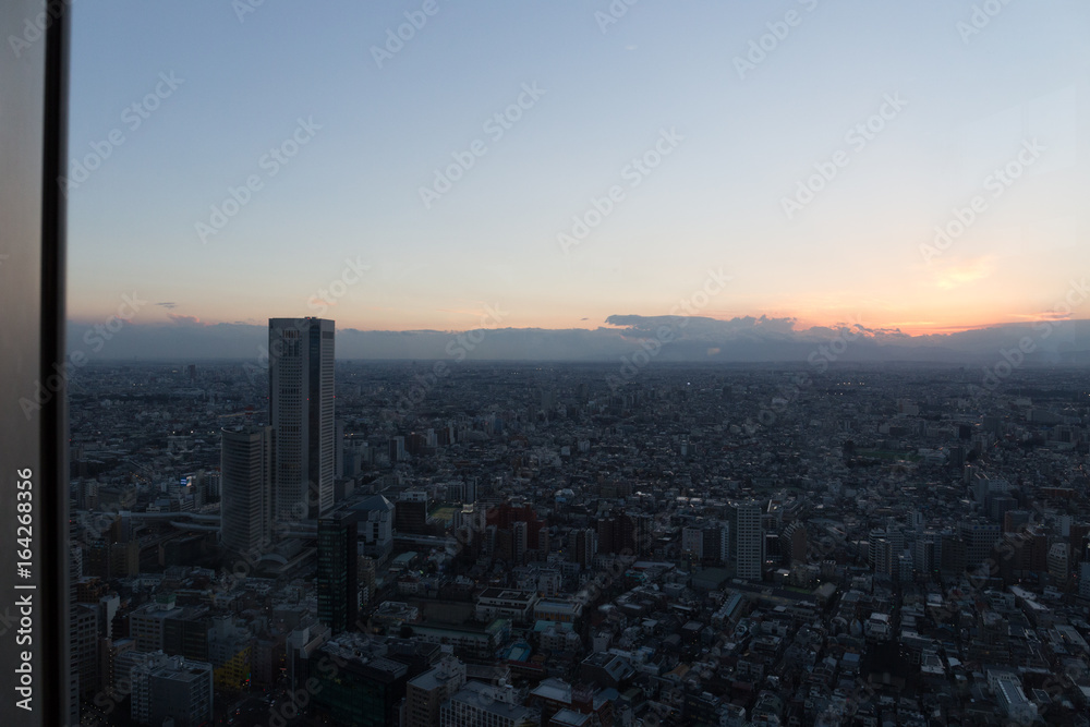 Sunset sky and dark city view through glass of Tokyo Metropolitan Government Building observation