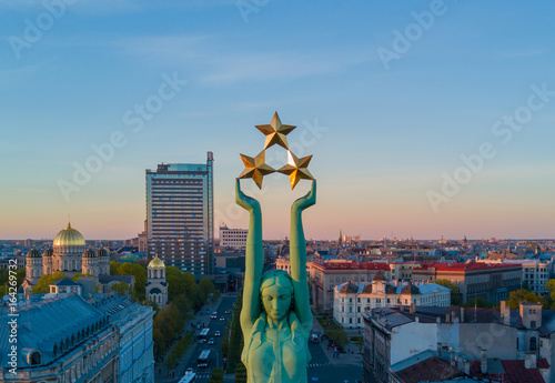Beautiful sunset view in Riga by the statue of liberty - Milda. Freedom in Latvia. Statue of liberty holding three stars over the city. Latvian spirit. photo