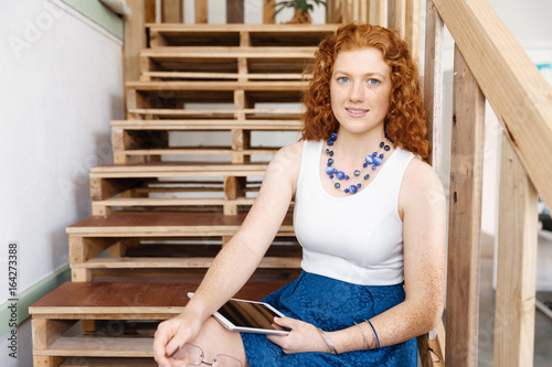 Portrait of young woman sitting at the stairs in office