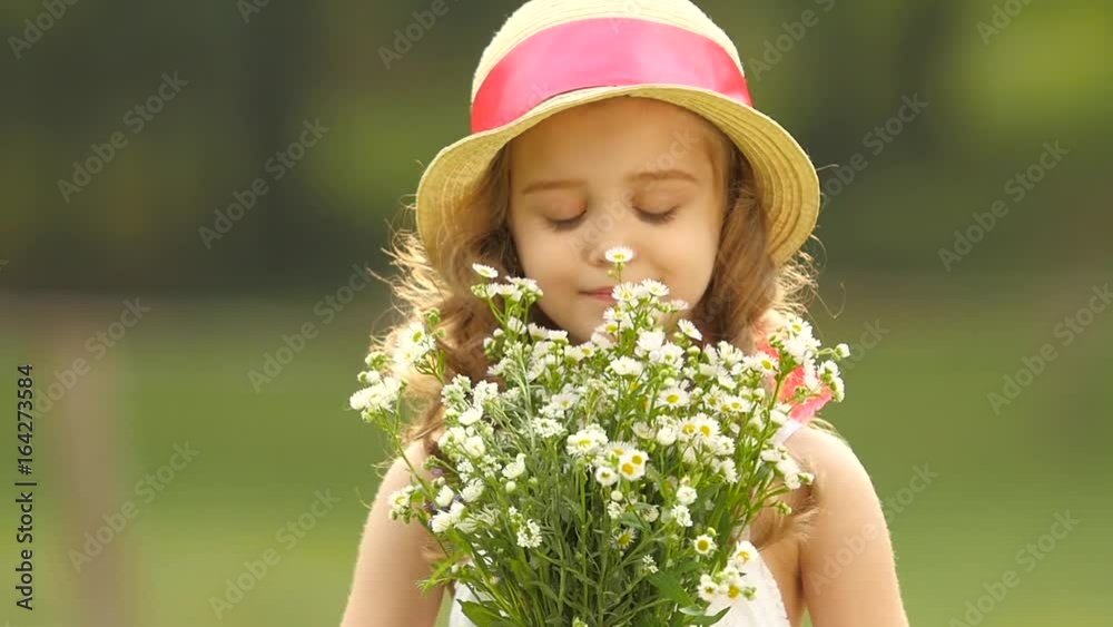 Child holds a bouquet of wildflowers in her hands, she smells them and smiles. Slow motion Child holds a bouquet of wildflowers in her hands, she smells them and smiles. Slow motion