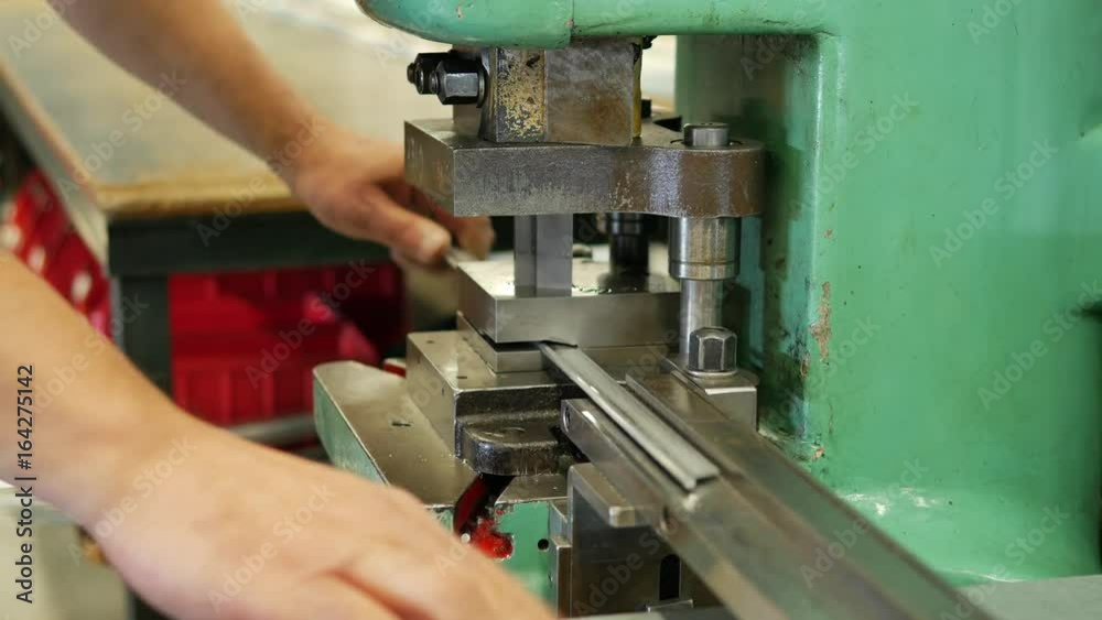 Workes cuts metal plates into small parts with a heavy duty machine Workes cuts metal plates into small parts with a heavy duty machine