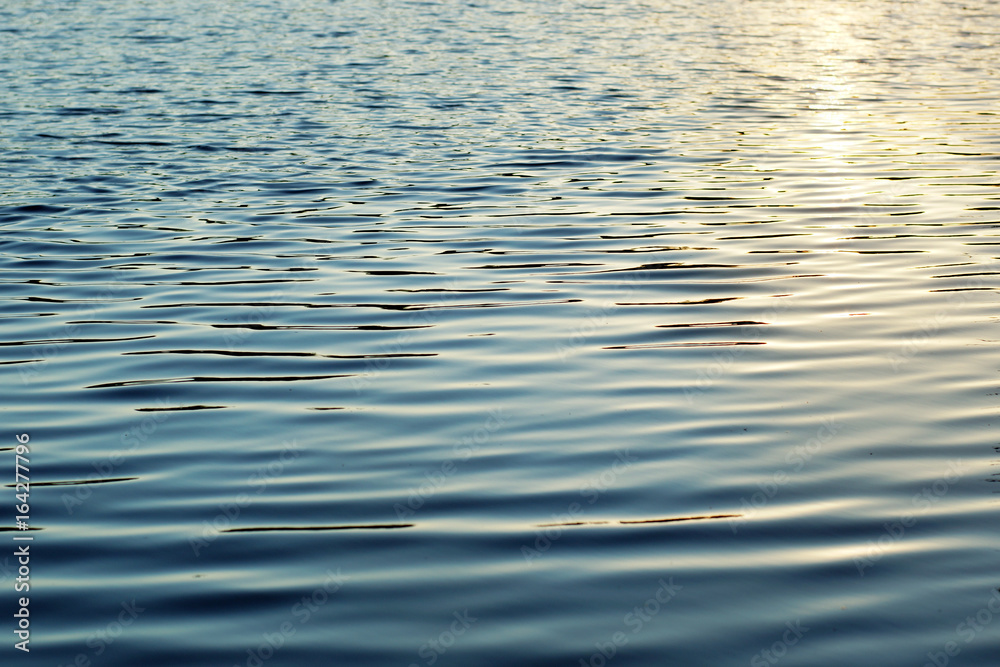 The water surface, illuminated by the sun, light waves and ripples on the water The water surface, illuminated by the sun, light waves and ripples on the water