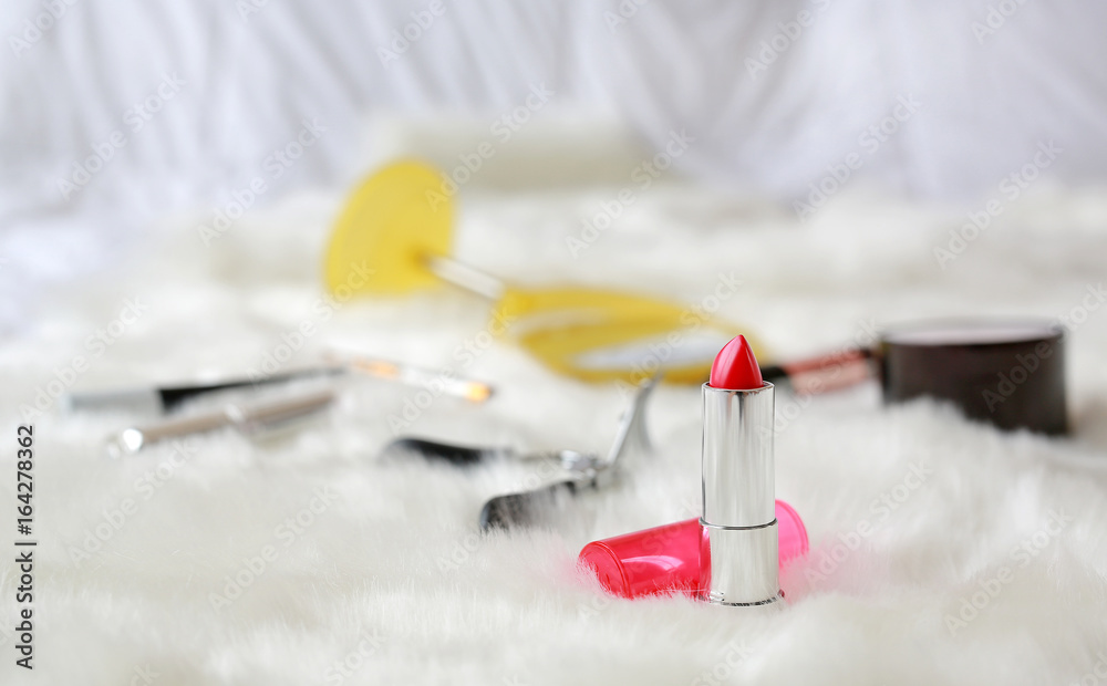 lipstick and Different makeup cosmetics on white artificial fur background focus at lipstick, Fashion concept. lipstick and Different makeup cosmetics on white artificial fur background focus at lipstick, Fashion concept.