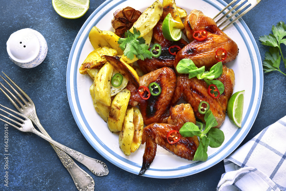 Grilled chicken wings with baked potato.Top view. Grilled chicken wings with baked potato.Top view.