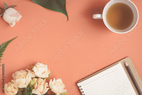 Flat lay Notebook and rose placed on a red desk