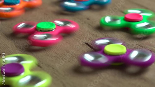 Dolly shot of a man that starts rotatting colored fidget spinners stress relieving toys on wooden background photo