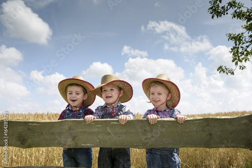three little cowboys outdoors in a field