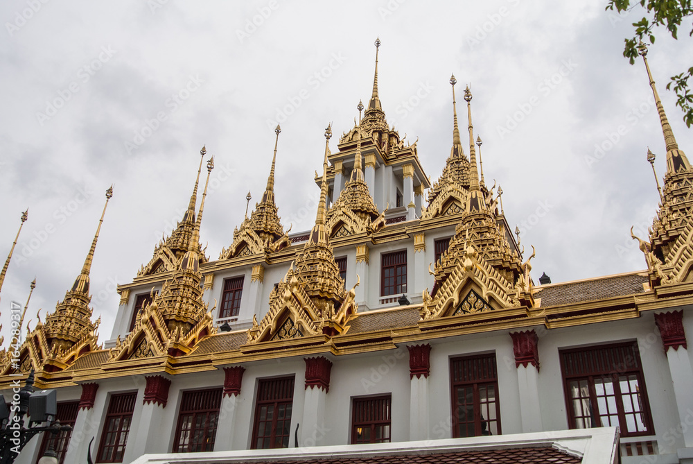 Naklejka premium Loha Prasat Wat Ratchanatdaram in Bangkok Thailand which means iron castle or monastery is composes of five towers, of which the outer, middle and the center tower contain large black iron spires. 