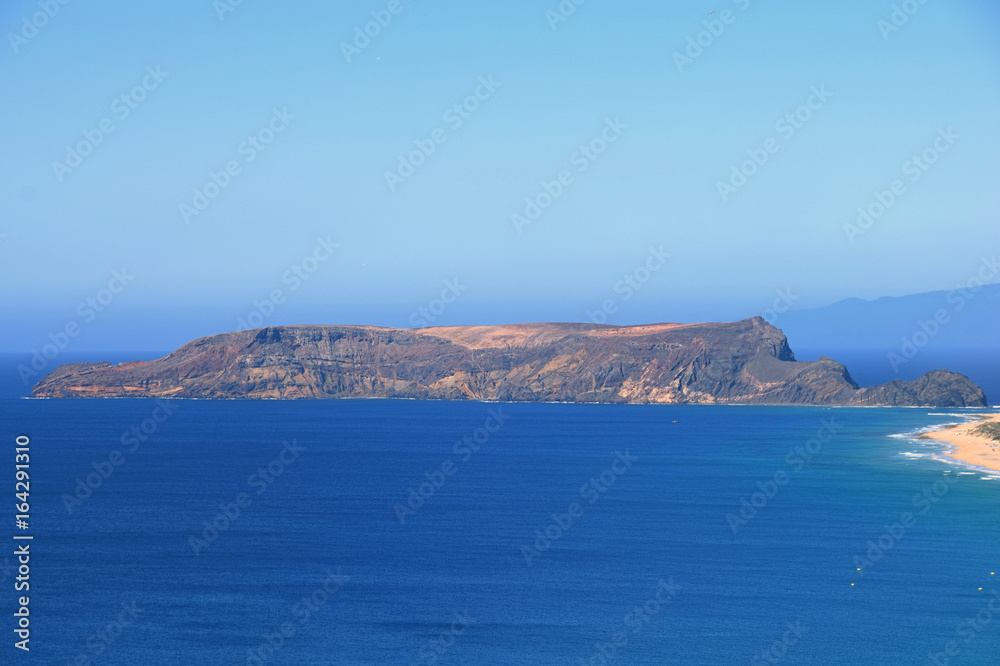 Ilheu da Cal barren uninhabitated island to the south of Ponta Da Calheta, Porto Santo with Madeira to the right on the horizon