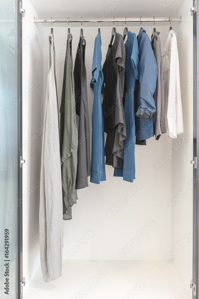 clothes hanging on rail in wooden white wardrobe