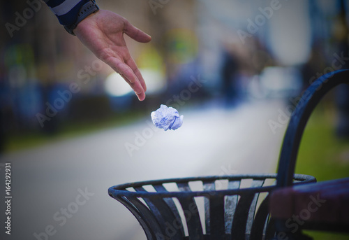 Hand is throwing trash into the basket photo