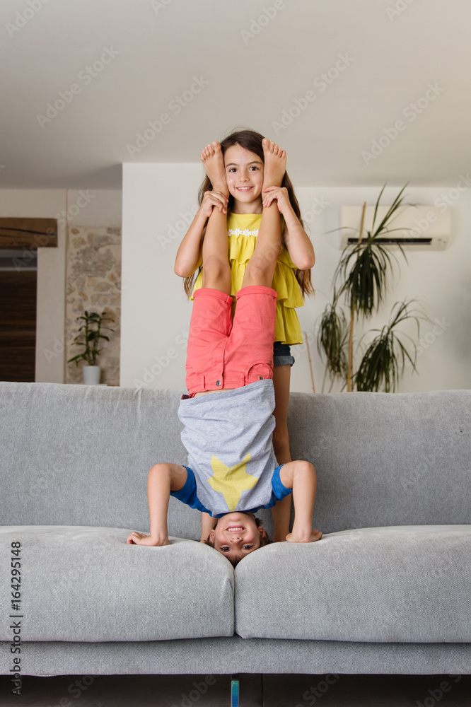 højttaler stykke Baglæns girl helping brother with headstand on couch Stock Photo | Adobe Stock
