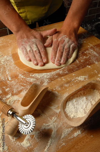 The chef prepares dough for fettuccine , soup and pizza photo