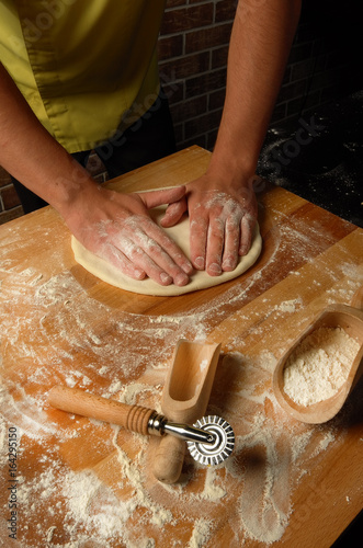 The chef prepares dough for fettuccine , soup and pizza photo