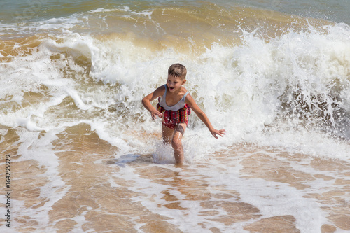 Little boy running in sea surf at the beach