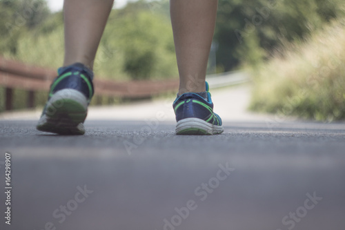 Feet of a girl walking on a countryside road. Piedi di una ragazza che cammina su una strada di campagna.