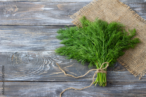 Obraz na plátne Bunch of fresh dill on a wooden surface with free space