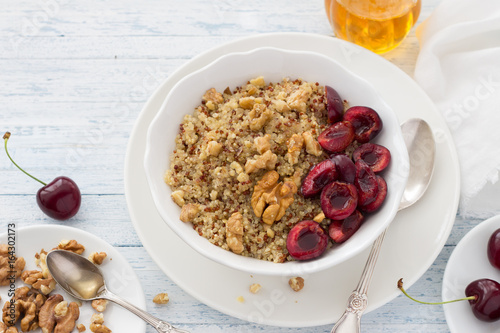 Healthy delicious vegan breakfast. Quinoa with fresh cherries, walnuts and honey on the blue background