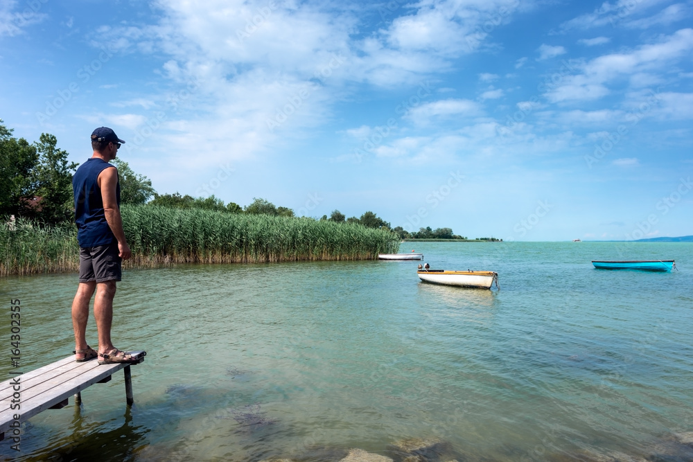 Adult man looks at Balaton Lake in the summer Adult man looks at Balaton Lake in the summer