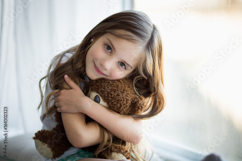 Fotografie Portrait of a beautiful girl with a brown toy bear