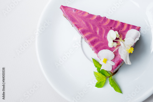 piece of cheesecake with blueberries on a white plate on a white background. view from above