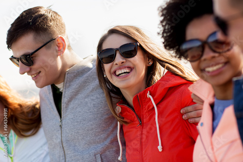 happy teenage friends in shades talking on street