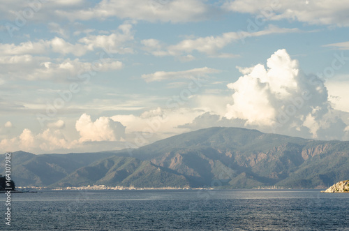 Summer panorama of the beach at sea and high mountains against the background of yachts and ships. Island in the middle of the sea. Ocean and islands © mykytivoandr