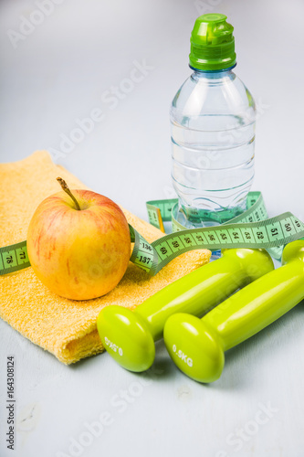 Dumbbells, an apple, a towel and a bottle of water