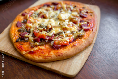 Pizza with salami, tomatoes, cheese on a wooden board