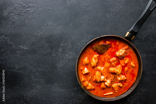 Frying pan with stewed meat on a black background and space for text