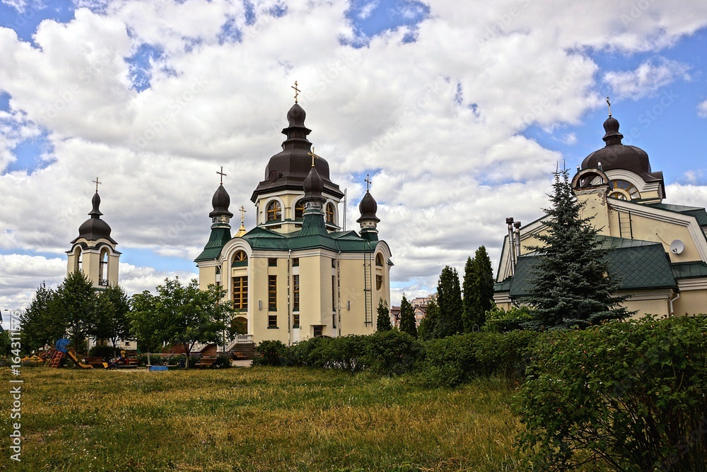 монастыри и церкви в зелёном парке на фоне неба и облаков