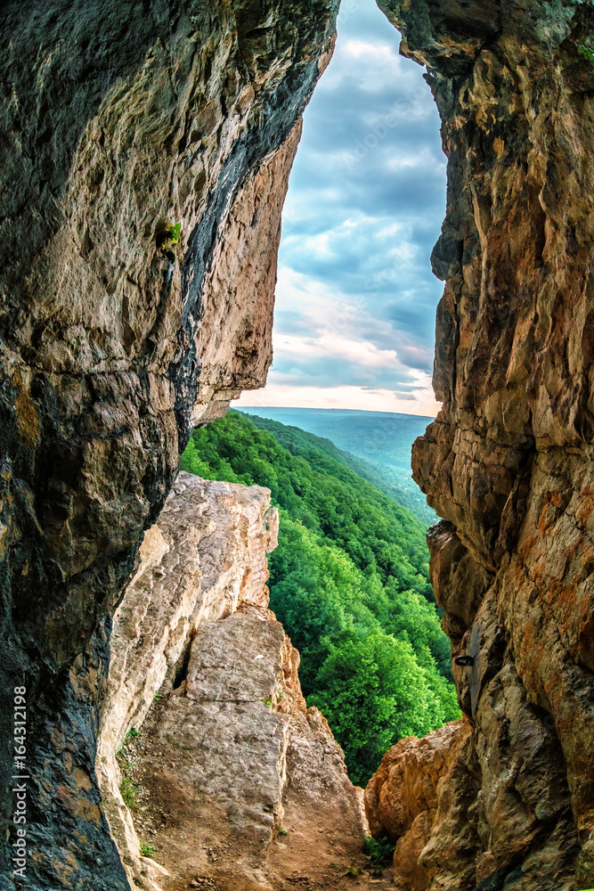 Beautiful scenic summer vertical landscape view of mountain forest from inside a weird rocky grotto in Caucasus mountains, Lenina Rock shelf, Russia