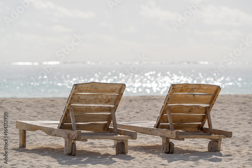 Empty wooden beach chairs on the tropical beach, vacation. Traveler dreams concept