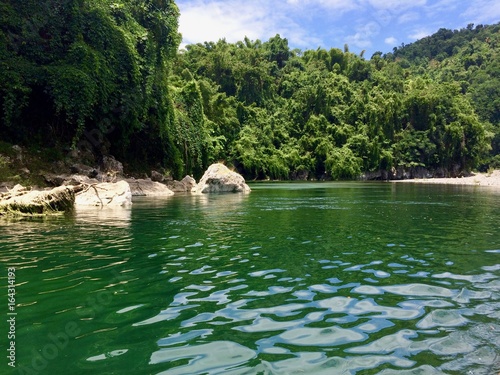Bamboo rafting on the beautiful tropical Rio Grande river in the sunny Portland Parish of the island of Jamaica (Caribbean) on a summer day with cloudy blue sky