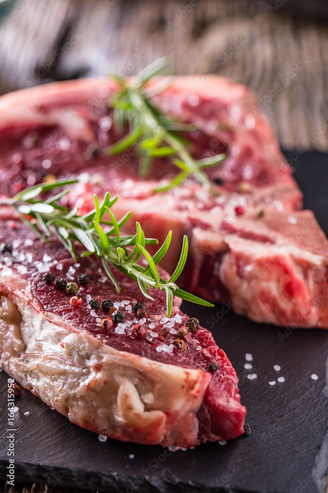 Beef raw steak. Raw fresh T-bone steak with salt pepper and rosemary Beef raw steak. Raw fresh T-bone steak with salt pepper and rosemary