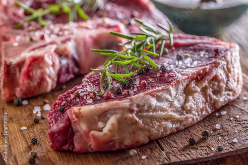 Beef raw steak. Raw fresh T-bone steak with salt pepper and rosemary