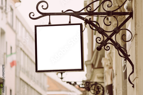 Blank square signboard, hanging from wrought iron bracket