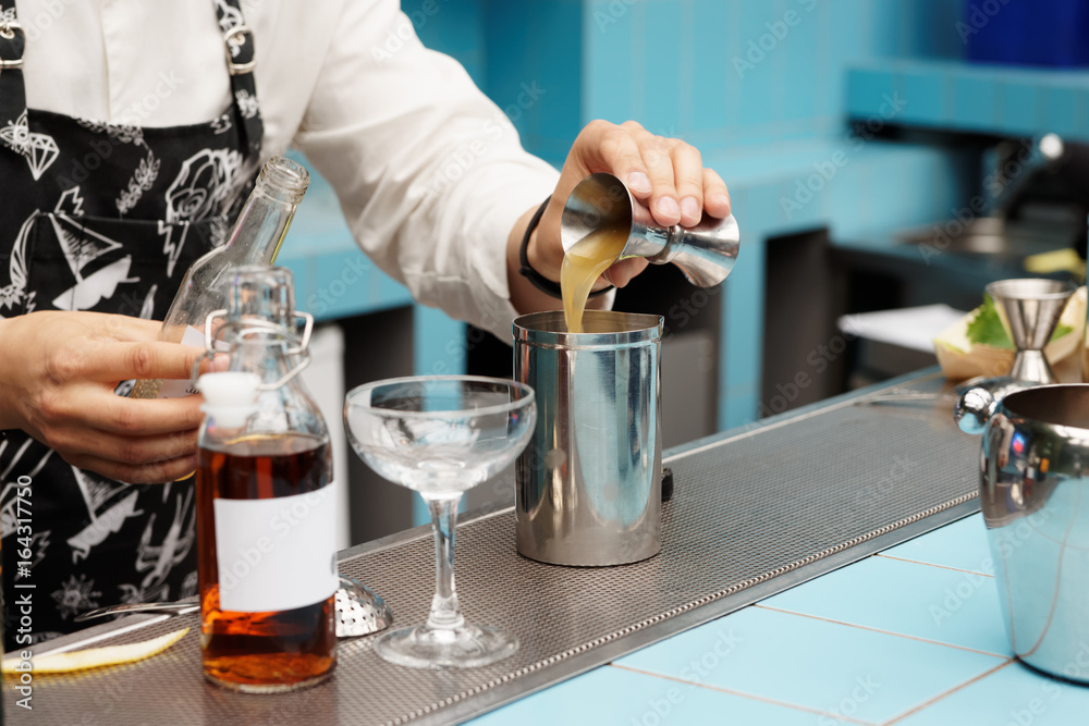 Bartender is pouring infusion into a mixing glass